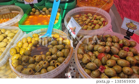 Selection of assorted marinated olives in plastic tubs with scoops at market stall for deli display and food packaging background Selection of assorted marinated olives in plastic tubs with scoops at market stall for deli display and food packaging background 138565930