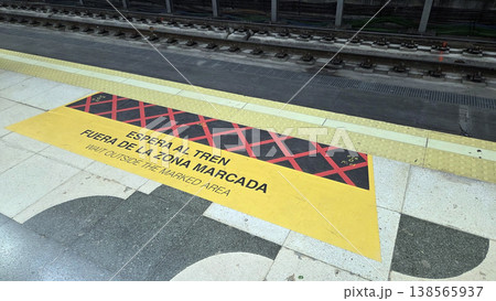 Madrid metro platform safety marking with yellow caution area and bilingual warning text for transit poster and public signage background 138565937