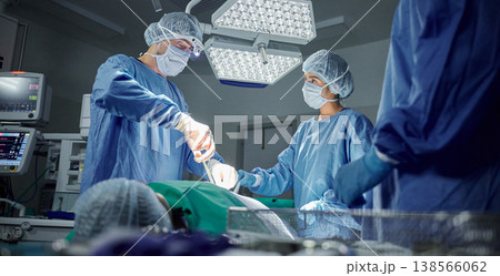 Teamwork, medical and doctors working on a surgery for healthcare treatment in a theatre room. Collaboration, career and professional surgeons doing an operation on a patient in a hospital or clinic. Teamwork, medical and doctors working on a surgery for healthcare treatment in a theatre room. Collaboration, career and professional surgeons doing an operation on a patient in a hospital or clinic. 138566062