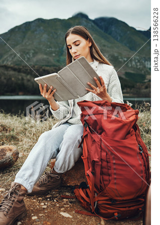Tablet, reading and woman hiking with backpack in nature on mountain for adventure and weekend trip. Digital technology, bag and female person from Canada checking information and trekking in forest. Tablet, reading and woman hiking with backpack in nature on mountain for adventure and weekend trip. Digital technology, bag and female person from Canada checking information and trekking in forest. 138566228