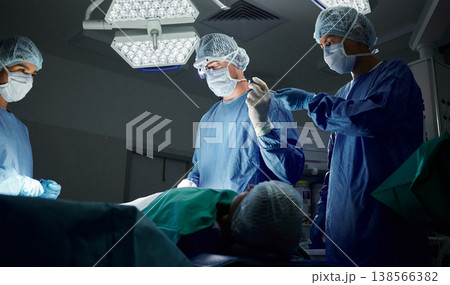 Teamwork, tools or doctors in surgery emergency procedure or healthcare operation in hospital at night. Giving, trust or surgeon in face mask or gloves helping in dark theatre room in medical clinic 138566382