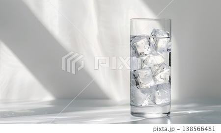 tall glass of water with ice cubes on the table, white background, light gray tabletop tall glass of water with ice cubes on the table, white background, light gray tabletop 138566481