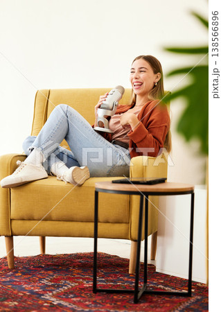 Microphone, smile and woman hosting a podcast on a chair by a wall in her modern home. Radio, broadcast and happy young female person hosting a journalism talk show in a recording space at her house. 138566896