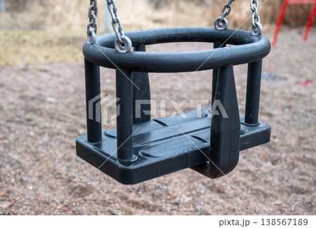 Empty toddler safety swing seat with chains in playground close up minimal childhood concept  138567189