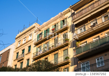 Sunlit residential building facade with balconies and green shutters in Barcelona urban architecture Sunlit residential building facade with balconies and green shutters in Barcelona urban architecture 138567202