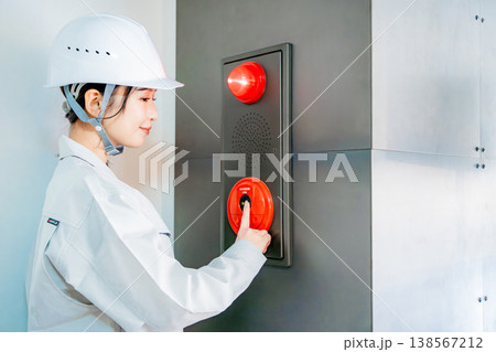 自動火災報知設備の点検をする作業着の女性 138567212