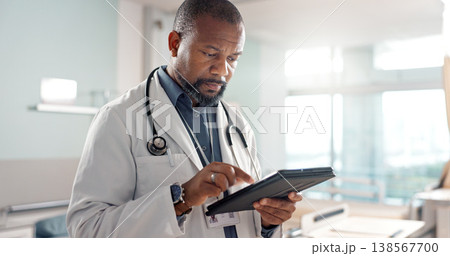 Healthcare, typing and a black man or doctor with a tablet for a medical app or communication. Mature, reading email and an African surgeon with technology for results, information or surgery advice 138567700