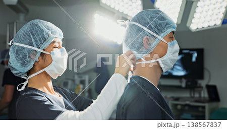 Surgery, hospital and doctors tie mask in operating room for medical service, preparation and operation. Healthcare team, safety scrubs and people with uniform for emergency, procedure and protection Surgery, hospital and doctors tie mask in operating room for medical service, preparation and operation. Healthcare team, safety scrubs and people with uniform for emergency, procedure and protection 138567837