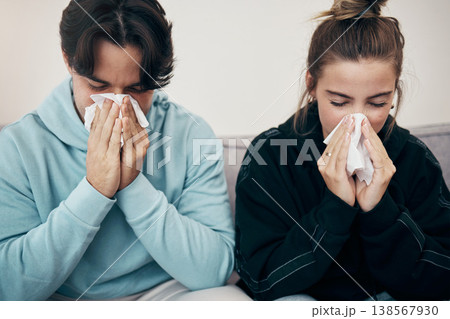 Couple, sick and couch with tissue, sickness and virus for infection, sinus and cold symptoms. Sneeze, blowing nose and allergy in living room sofa, hayfever and healthcare for disease, man and woman 138567930