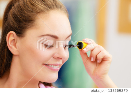 Woman applying black eye mascara to her eyelashes 138569879