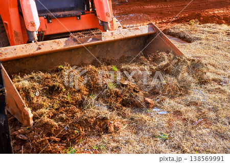 Heavy machinery works to move dirt debris in rural location during landscaping work with soil grass land clearing, 138569991