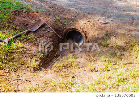 Small pipe lets water flow into cleaning drainage trench dirt path nearby, soil 138570005