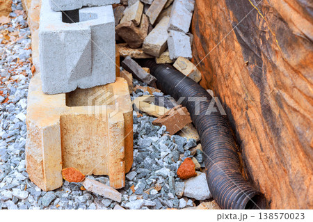 Blocks of concrete stones are arranged next to long black drainage pipe at work area Blocks of concrete stones are arranged next to long black drainage pipe at work area 138570023