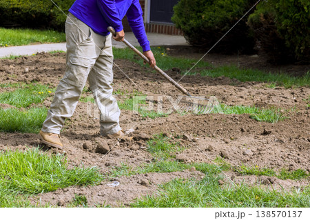 Worker works in yard to prepare soil for planting new seeds grass in autumn season. 138570137