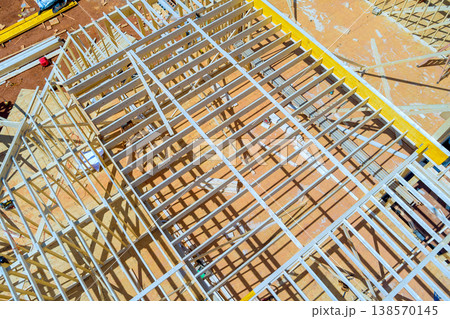 Workers install wooden beams at construction site during roof trusses tools materials are scattered around. 138570145