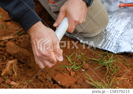 Worker is gluing PVC pipe with hands holding pipe in an outdoor space during connects water pipe Worker is gluing PVC pipe with hands holding pipe in an outdoor space during connects water pipe 138570215