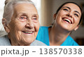 Happy caregiver and senior woman laughing together in a room. Warm atmosphere and trust. Concept of healthcare, relationship, and comfort. 138570338