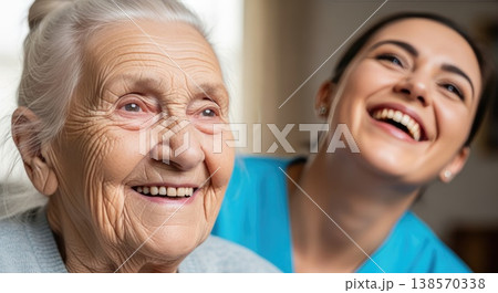 Happy caregiver and senior woman laughing together in a room. Warm atmosphere and trust. Concept of healthcare, relationship, and comfort. 138570338