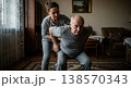 Adult daughter helping her elderly father perform light physical exercises at home. Daily care routine and support. Concept of rehabilitation and senior health. 138570343