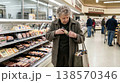 Old woman grocery item inside clothing in store. Concept of theft poverty and survival behavior. 138570346