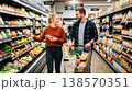 Family choosing food in a supermarket while focusing on discounts and offers. Routine shopping and budgeting. Concept of value and savings. 138570351