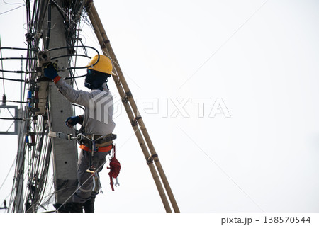 Electricians work on utility poles with safety as their top priority. 138570544