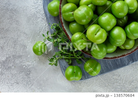 Tkemali, green cherry plum, in a bowl, on a gray table, top view, natural light, no people, 138570684