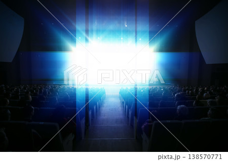 Audience watching a bright presentation in a large theater during an evening event Audience watching a bright presentation in a large theater during an evening event 138570771