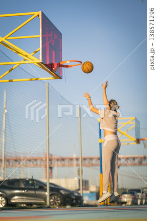 Woman jumping shooting basketball on outdoor court 138571296