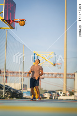 Young man playing basketball, scoring point at outdoor court 138571304