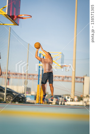 Young man playing basketball, shooting ball on court 138571305