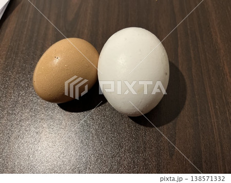 Comparison of natural farm fresh brown egg and industrially produced perfect white egg on dark wood contrast 138571332