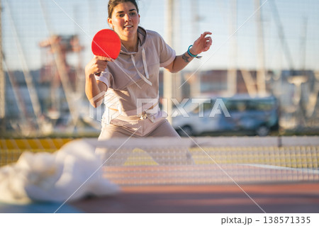Young woman enjoying active table tennis game outdoors Young woman enjoying active table tennis game outdoors 138571335