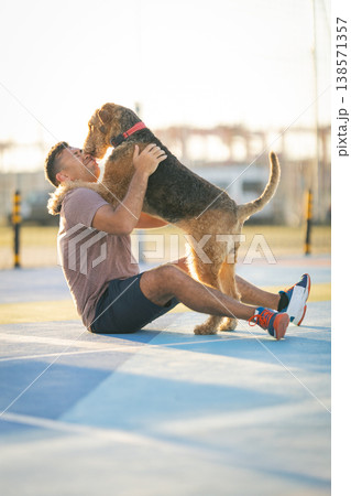 Man and airedale terrier dog embracing on court Man and airedale terrier dog embracing on court 138571357