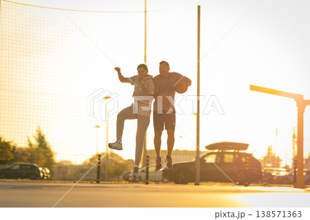 Couple jumping with basketball having fun outdoors Couple jumping with basketball having fun outdoors 138571363
