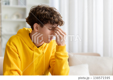 Stressed teen guy suffering headache, pressing fingers to forehead with eyes closed 138571595