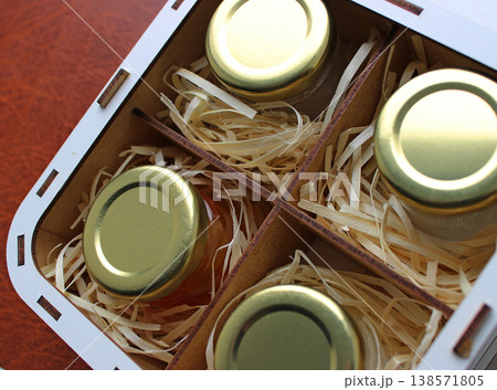 Souvenir from Home Apiary. Set of Different Types of Honey in Identical Jars in a Gift Case on Brown Background Souvenir from Home Apiary. Set of Different Types of Honey in Identical Jars in a Gift Case on Brown Background 138571805
