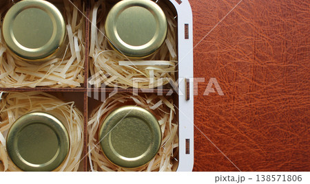 Plywood Box With Compartments That Hold Small Jars Of Homemade Honey Wrapped In Wood Chips. Honey Souvenir Set on Leather Surface Copy Space Image 138571806