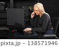 Female IT technician on a call while working on server hardware and laptop in a data center 138571946