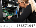 Female IT technician upgrades and repairs server hardware in a data center, focused on diagnostics and maintenance 138571947