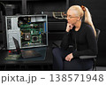 Female IT technician examines open server hardware with laptop, RAM modules, and tools for maintenance 138571948