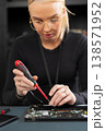 Female IT technician in her twenties repairs a laptop with precision screwdriver 138571952