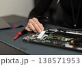 IT technician in his thirties repairs a laptop internals, upgrading components and diagnosing hardware issues 138571953