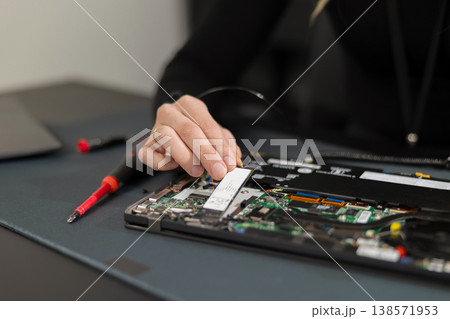 IT technician in his thirties repairs a laptop internals, upgrading components and diagnosing hardware issues 138571953