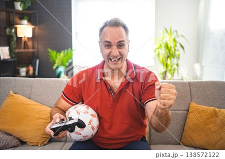 Middle age Caucasian man playing soccer video game at home 138572122