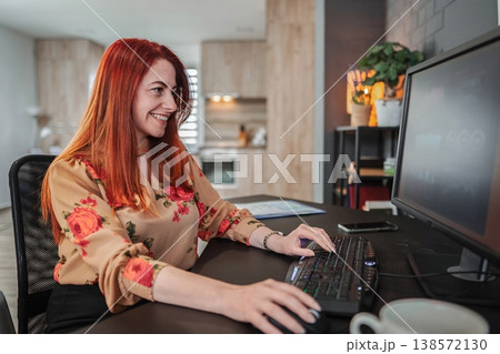 Happy young woman working from home, typing on a computer keyboard Happy young woman working from home, typing on a computer keyboard 138572130