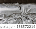 Grey silk sheet on a bed. Luxury bed linen. Hotel bedroom concept. Comfortable bed with fabric and two pillows. Double bed for couple. Rumpled bedding after sleeping. Two pillows on the sofa. 138572219