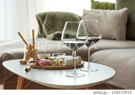 Cozy living room with two glasses of red wine and cheese on table Cozy living room with two glasses of red wine and cheese on table 138572653