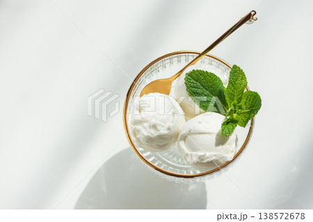 Vanilla Ice Cream in Elegant Glass Bowls on White Table with Sunlight 138572678