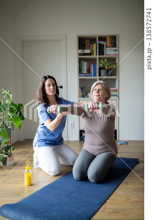 Physiotherapist helping senior woman during rehabilitation exercise at home. Physiotherapist helping senior woman during rehabilitation exercise at home. 138572741